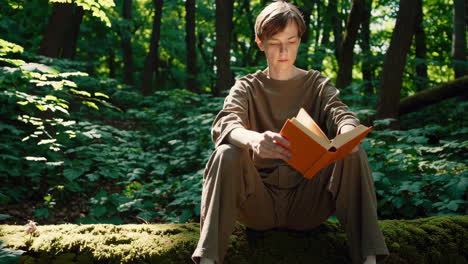 person reading a book on a mossy log in a peaceful forest