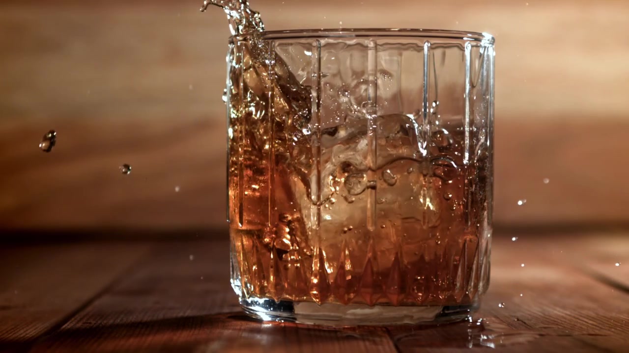 Slow motion di ghiaccio e whisky che si versano in un bicchiere