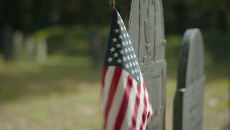 Close-up-of-an-American-Flag-next-to-an-old-tombstone-from-the-1800's