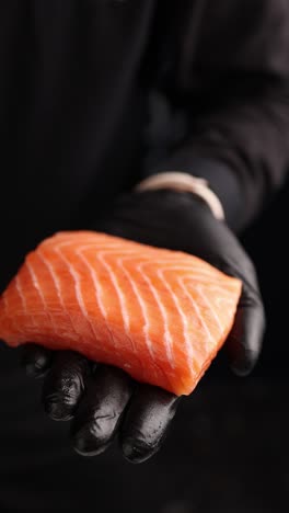 chef holding a piece of raw salmon