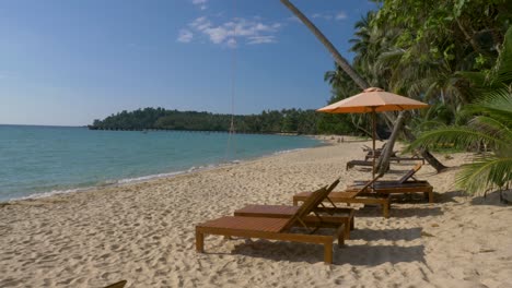 wide shot of beach beds with umbrella on white sandy beach