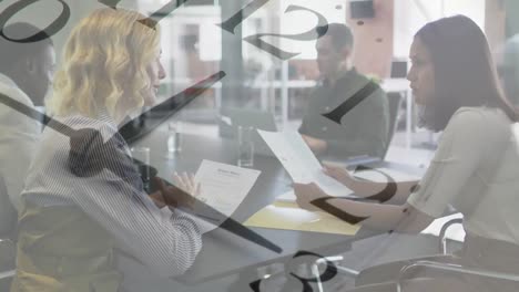 Animation-of-clock-over-two-diverse-businesswomen-talking-in-office-meeting