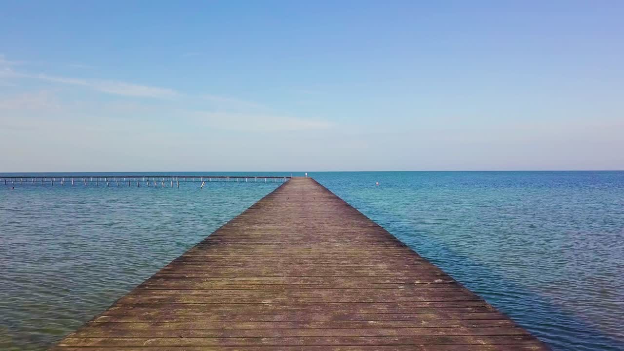 A flight over a wooden pier in the sea.