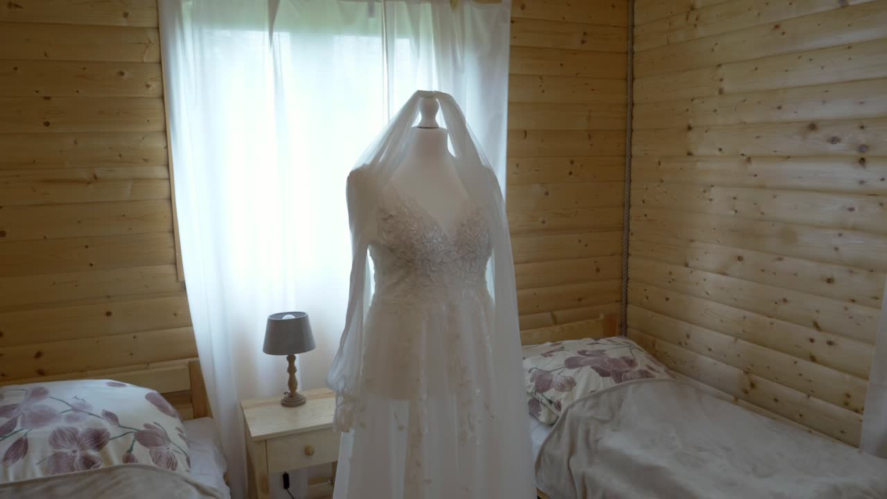 Abito da sposa su manichino in stanza in stile boho con velo fluttuante