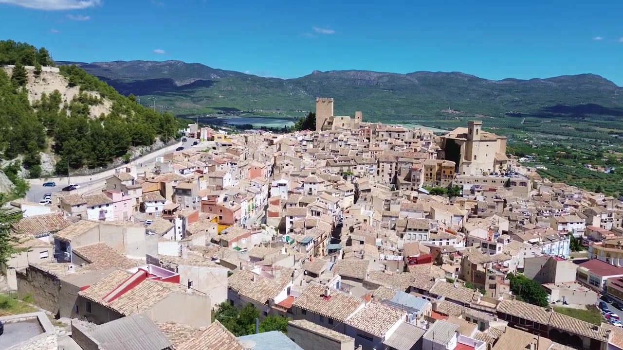 Vista aerea con drone della storica città di Calasparra nel sud della Spagna, con case del centro storico, castello medievale, paesaggio montano, architettura tradizionale, destinazione di viaggio e un panoramico panorama urbano.