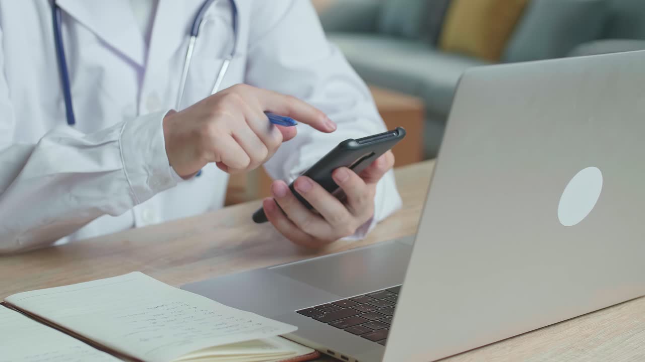 Hands Man Doctor Use Mobile Phone And Write On Note Book During Work On Laptop Computer, Video In 4K