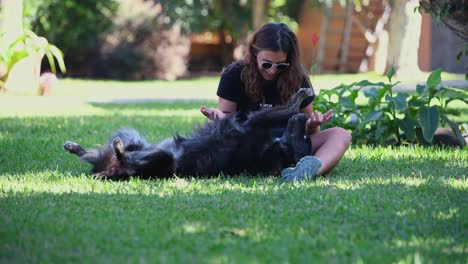 a young caucasian woman caresses her dog in the garden of a house on a sunny day