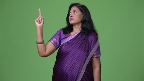 mature beautiful indian woman pointing up while thinking