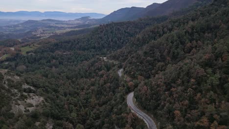 Winding-road-through-autumn-forest-in-Vinyoles-and-Sobremunt,-Barcelona,-Spain,-aerial-view