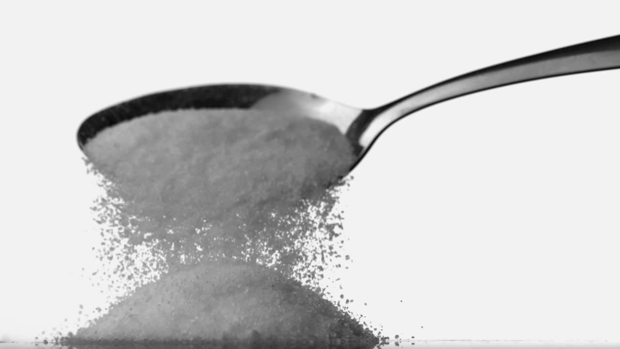Spoon pouring sugar powder on pile of sugar
