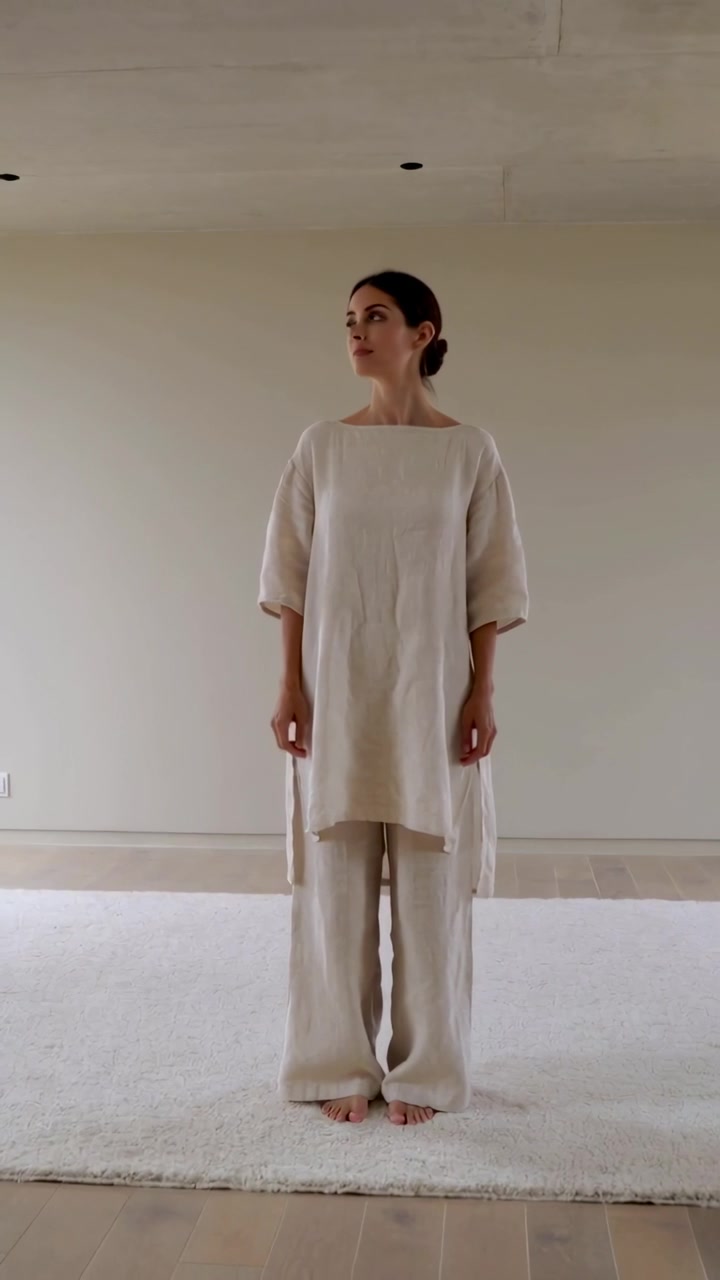 Blickwechsel nach kurzem Blick: Eine Frau in cremefarbenem Leinen-Outfit dreht sich für eine Pose auf einem Teppich zur Seite.