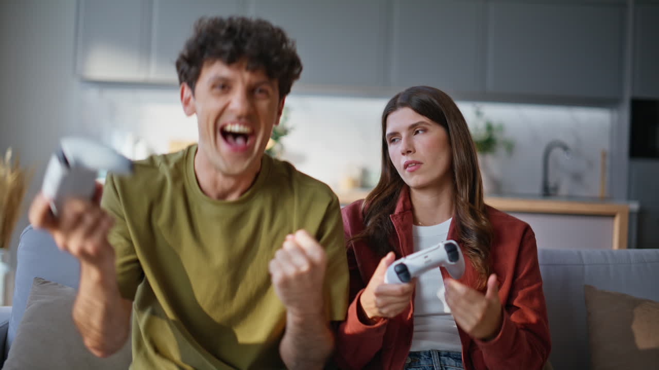 Gamers spouses playing video games using controllers sitting cozy couch together