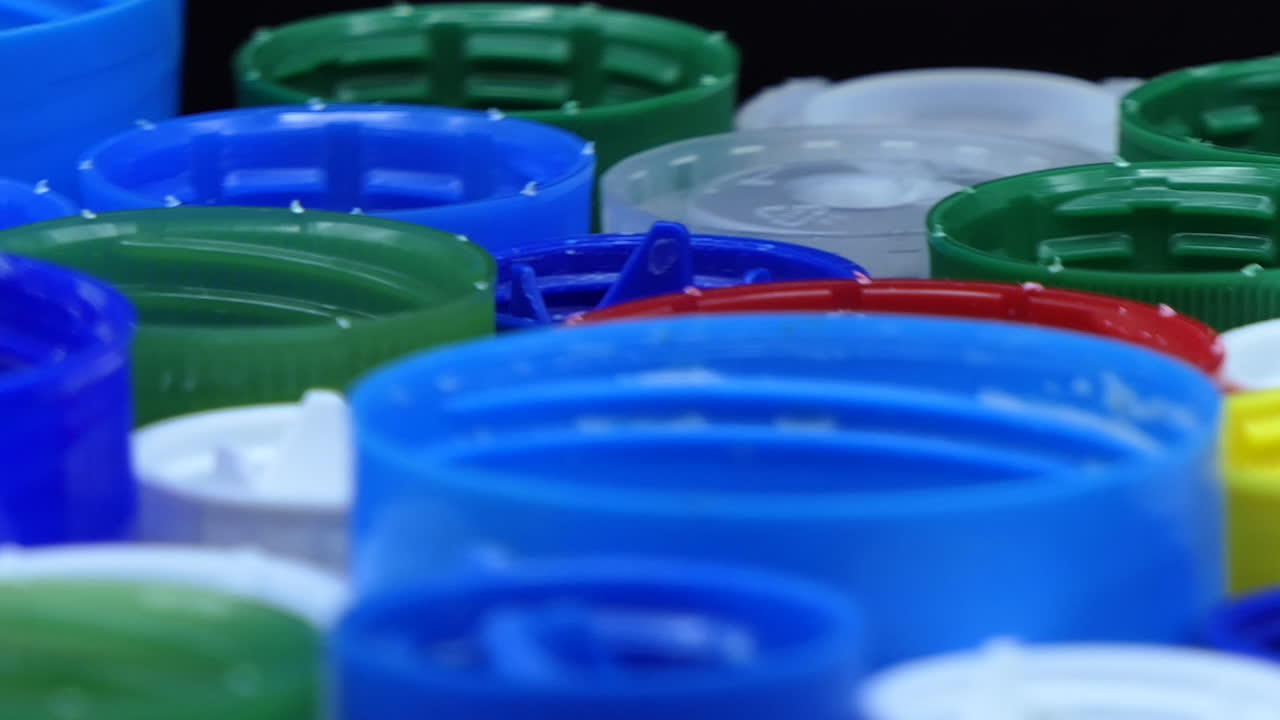 Used caps from used plastic bottles of different colors that turn in front of a black background
