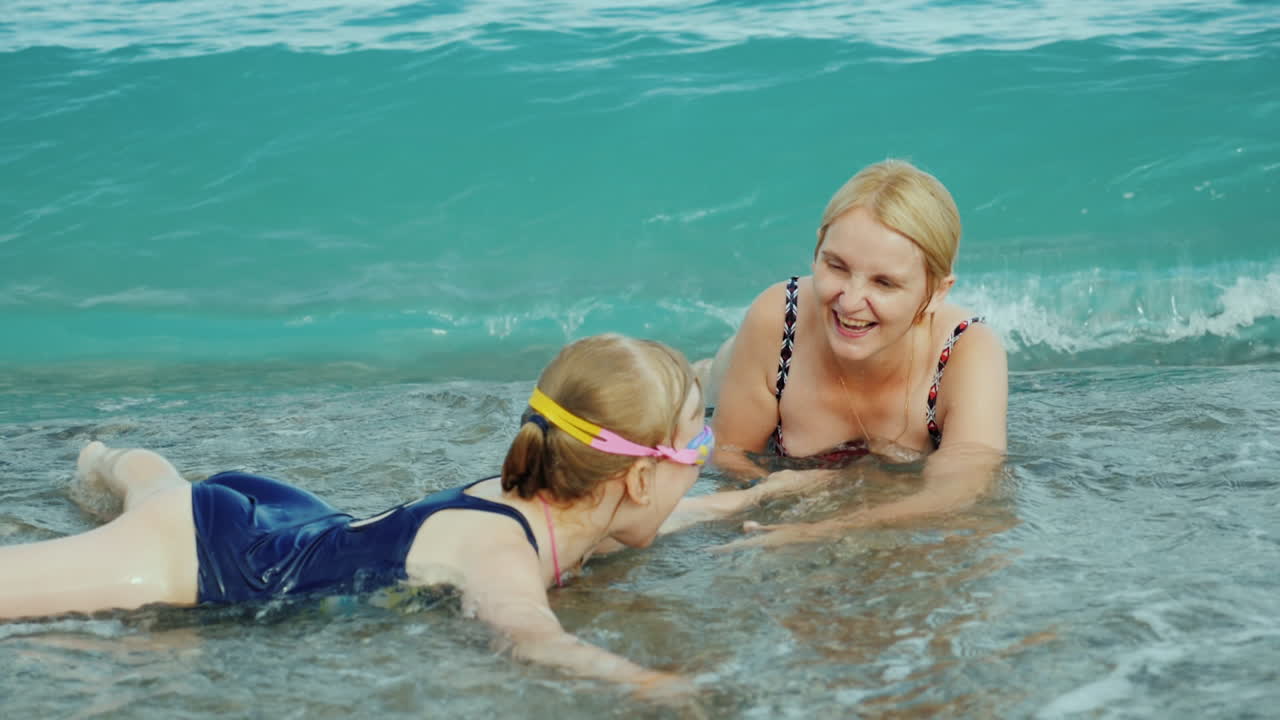 엄마와 딸은 아이들과 함께 바다의 서핑 파도에서 즐거운 시간을 보내고 있습니다 슬로우 모션 비디오