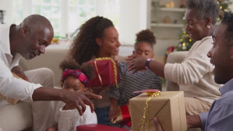 multi-generation family celebrating christmas at home opening presents together