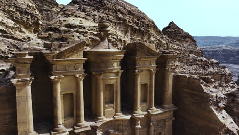 Aerial-view-around-a-person-standing-on-top-of-the-Al-Dayr-monastery,-in-sunny-Petra,-Jordan