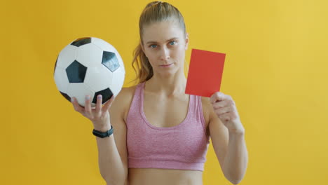 woman holding soccer ball and red card