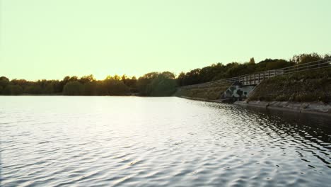 soft ripple on a clear lake during golden hour as the sun sets in the distance