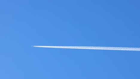 jet leaves contrail across clear blue sky