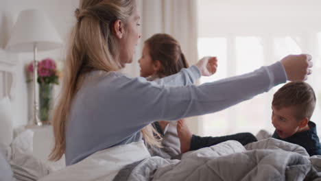 Familia-Feliz-Con-Niños-Saltando-En-La-Cama-Jugando-Con-Madre-Y-Padre-Divirtiéndose-El-Fin-De-Semana-Por-La-Mañana-Niños-Pequeños-Emocionados-Disfrutando-Del-Juego-Con-Sus-Padres-En-Casa-4k