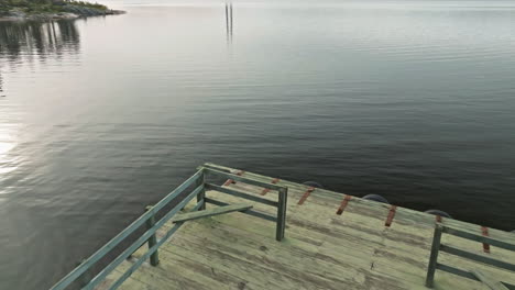 fly over campervan over calm lakeshore near wooden jetty in sweden