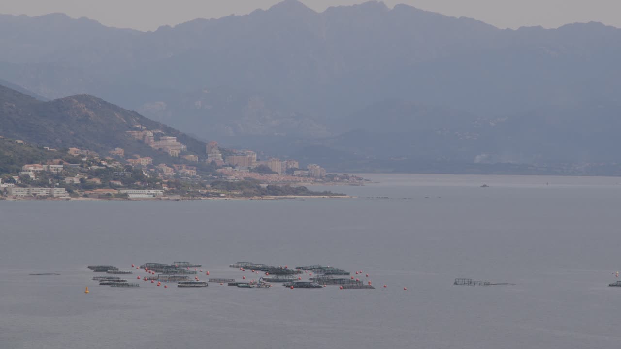 Coastal landscape with fish farm and city