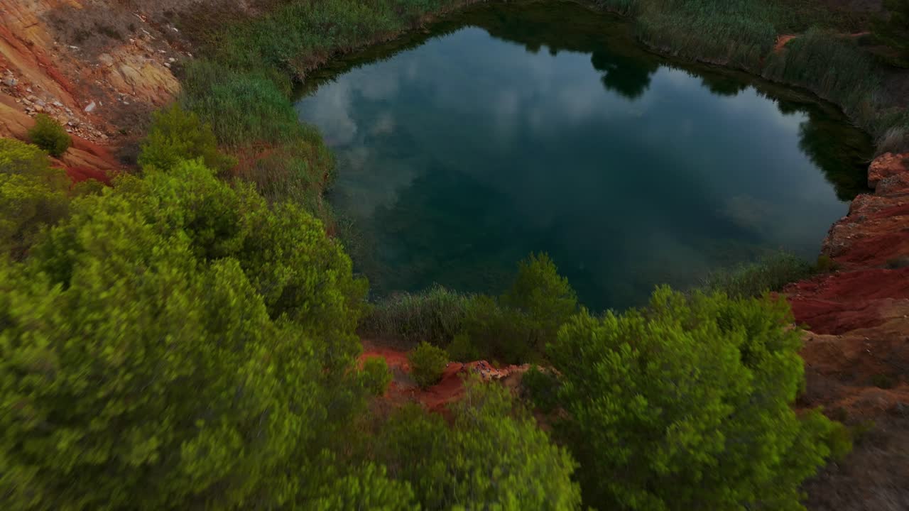 otranto, puglia, italia - una vista panorámica de la cueva de bauxita con un lago que refleja el cielo nublado - avión no tripulado volando hacia adelante