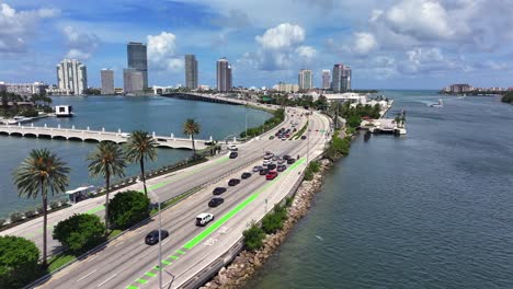 drone flight over river bay in miami with macarthur causeway and downtown in background. sunny day in summer season. traffic on road following to skyscrapers. wide shot