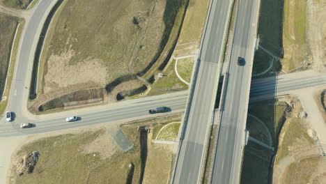 An-overhead-view-captures-the-quiet-dynamics-of-a-highway,-illustrating-a-crisscross-of-roads-amidst-a-rural-backdrop