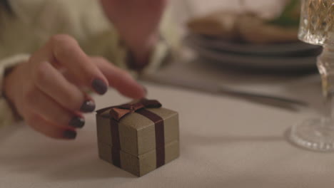 surprised woman opening engagement ring box during christmas dinner at home