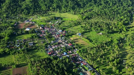 aerial view of provincial village settlement amid lush greenery and hilly landscape at timbaan, san andres, catanduanes, philippines.