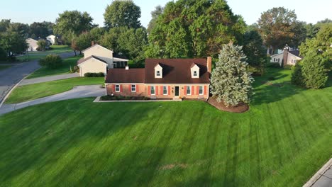 aerial view of a brick house with green lawn and trees in a suburban setting