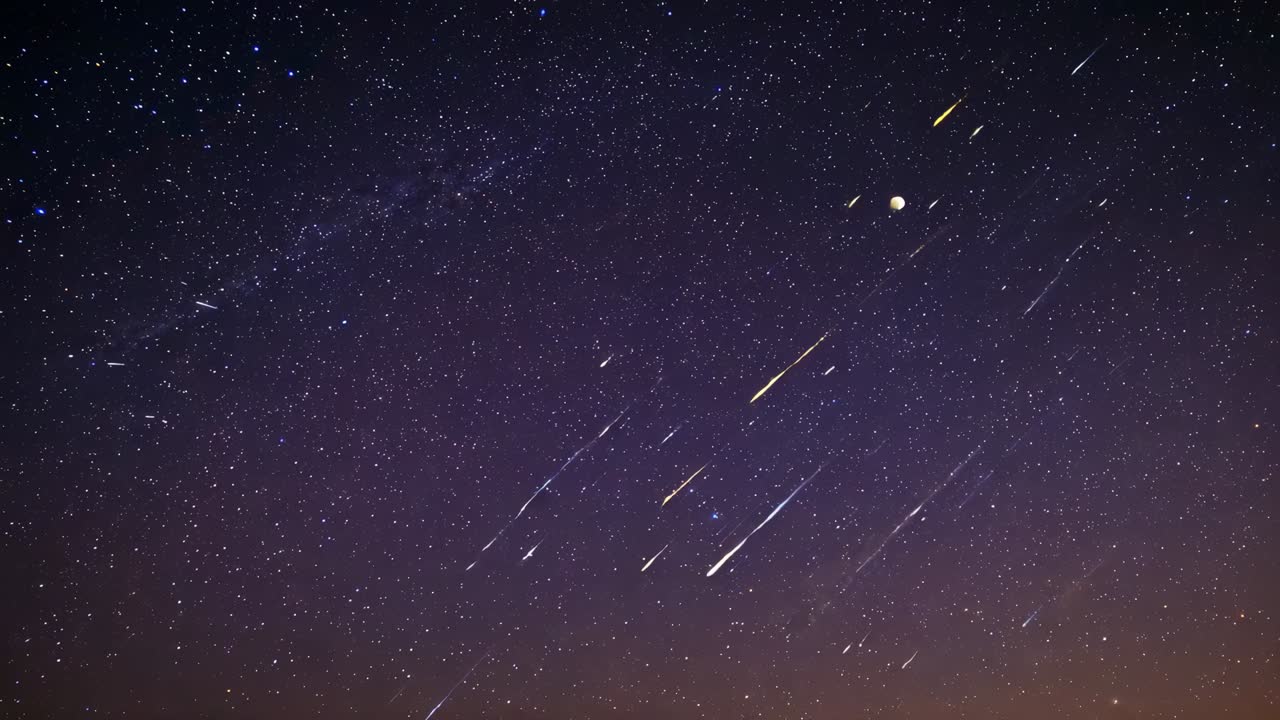 Meteors streaking after short burst across rural night sky, showing Milky Way and horizon glow