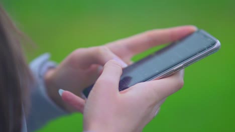 girl holding and typing text on smartphone - woman using a touchscreen cellphone