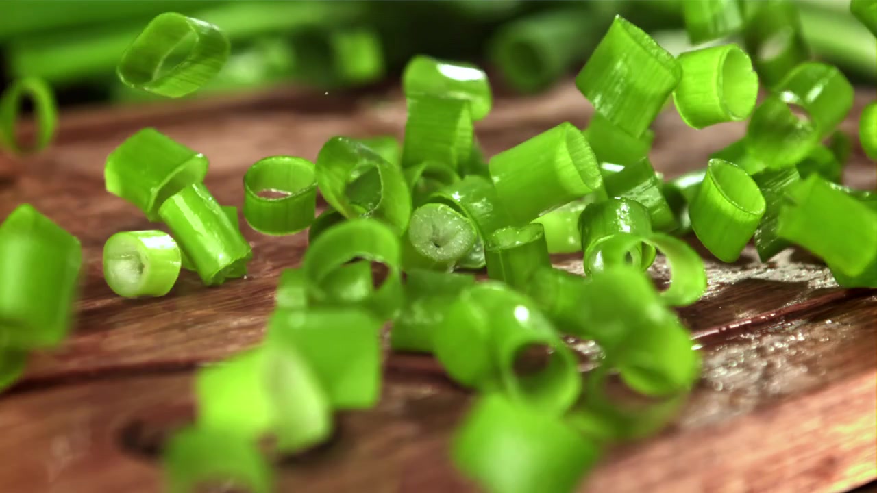 Chopped Green Onions Falling onto a Wooden Cutting Board in Slow Motion