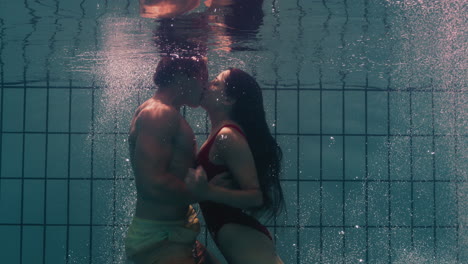 underwater couple kissing in swimming pool young people in love enjoying romantic kiss passionate lovers submerged in water floating with bubbles in playful intimacy