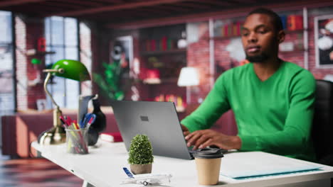 vertical video african american employee seated at home office using his pc,