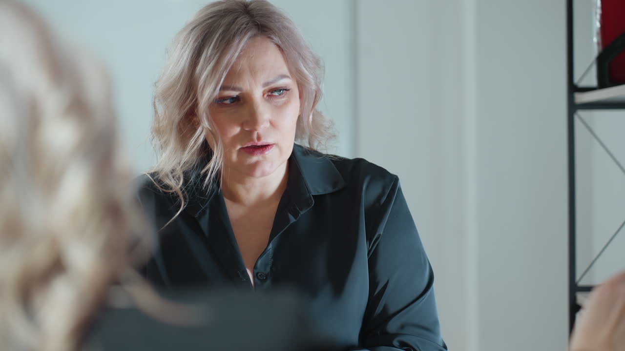 close up real estate professional explaining project to client across desk in well lit office setting showing focused expression while discussing miniature building model