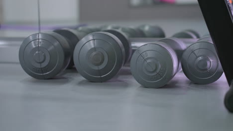 close-up of multiple dumbbells neatly arranged on gym flooring, reflecting in a mirror, the setup highlights strength training equipment used for fitness workouts