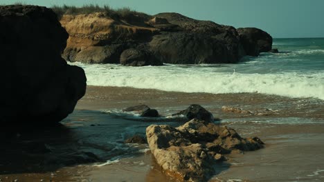 undulating waves crashing on to beach with rocks in balochistan