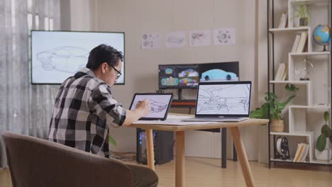 vista lateral de un hombre asiático dibujando un nuevo concepto de diseño de automóvil en una tableta en el estudio con televisión y computadoras muestra modelo de automóvil eléctrico 3d