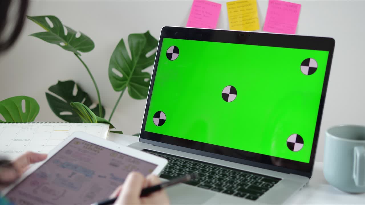 mujer usando una computadora portátil con pantalla verde en su escritorio en casa