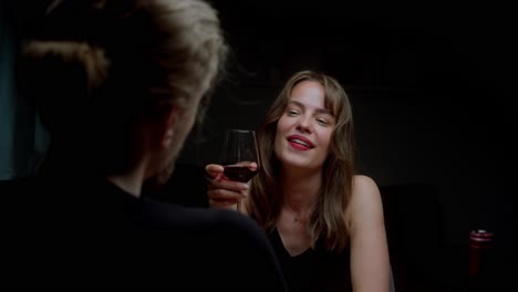 a woman laughs at a man's jokes while they enjoy a bottle of red wine together - close up