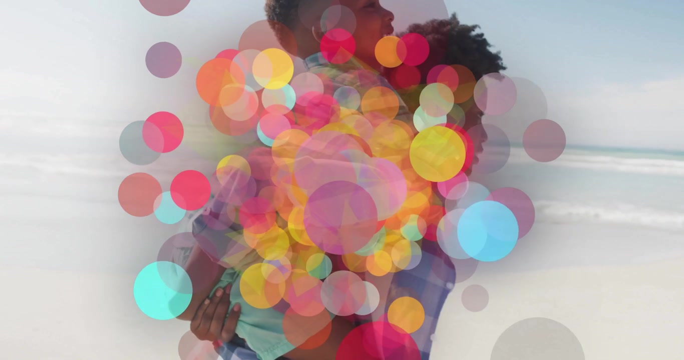 Donna che porta in braccio il figlio camminando lungo la spiaggia e attivando una sequenza bokeh animata per una dimostrazione tecnologica.