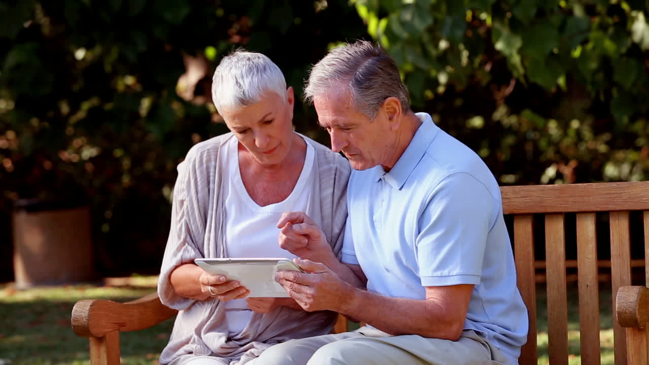 coppia matura che usa un tablet su una panchina