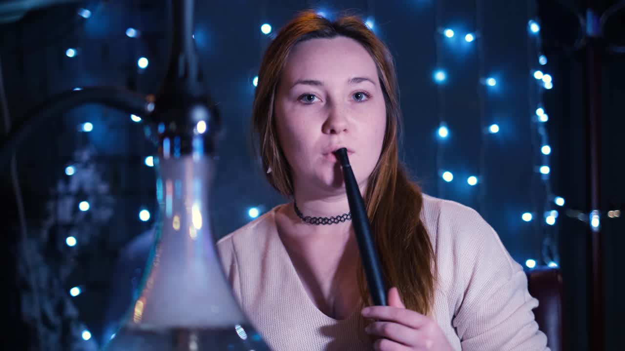 mujer disfrutando de narguile en un ambiente nocturno acogedor