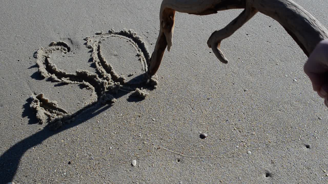 L'iscrizione SOS sulla sabbia. Riprese sulla spiaggia
