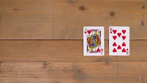 una persona que coloca un royal flush con corazones en una mesa de madera para educar al espectador sobre cómo jugar al póquer