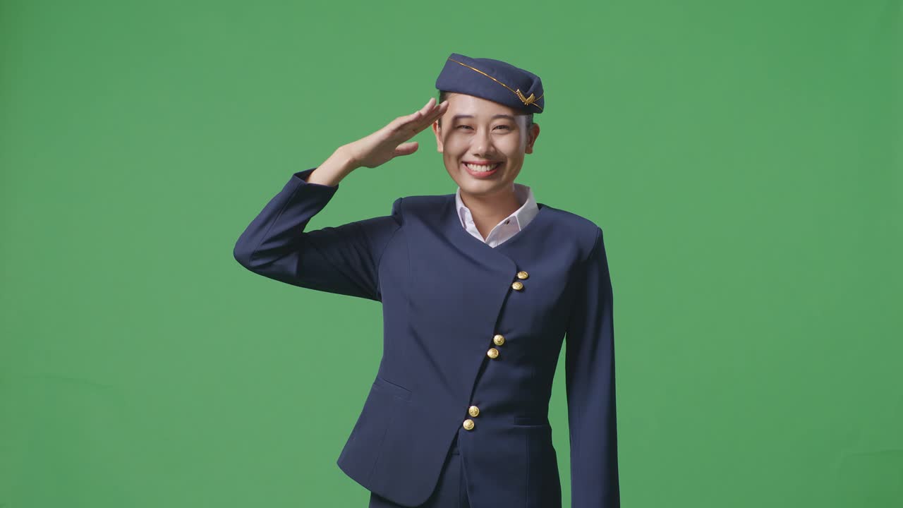 아시아 여성 승무원은 존경스럽고, 녹색 스크린 배경 스튜디오에 서서 인사를합니다.