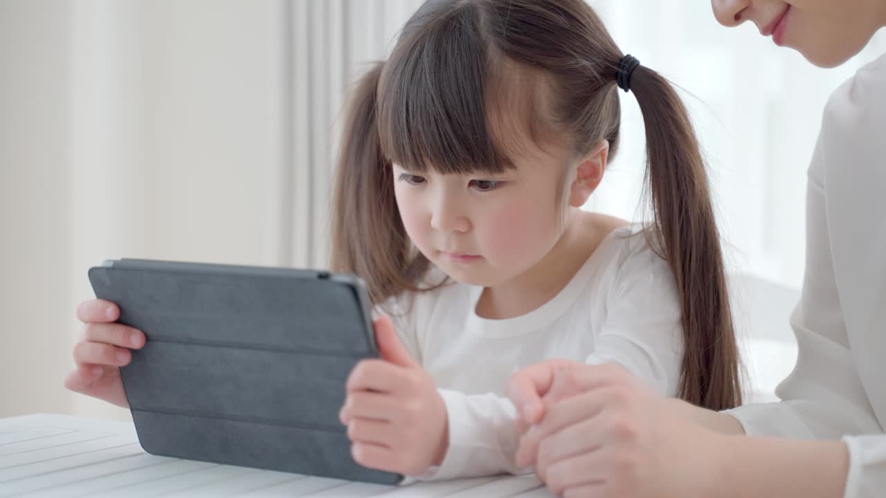 태블릿 컴퓨터를 사용하는 젊은 아시아 어머니와 딸